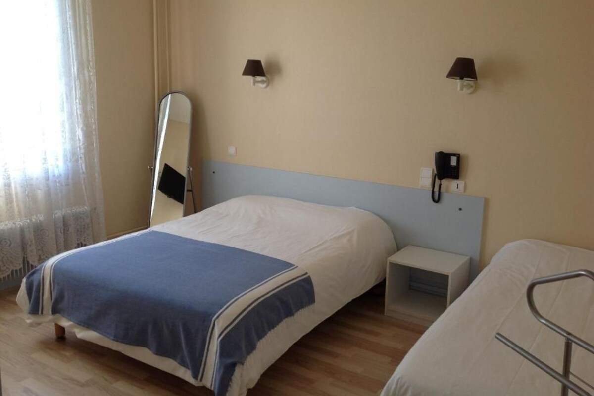 A hotel room with a bed, bedside table, lamp, and a mirror.