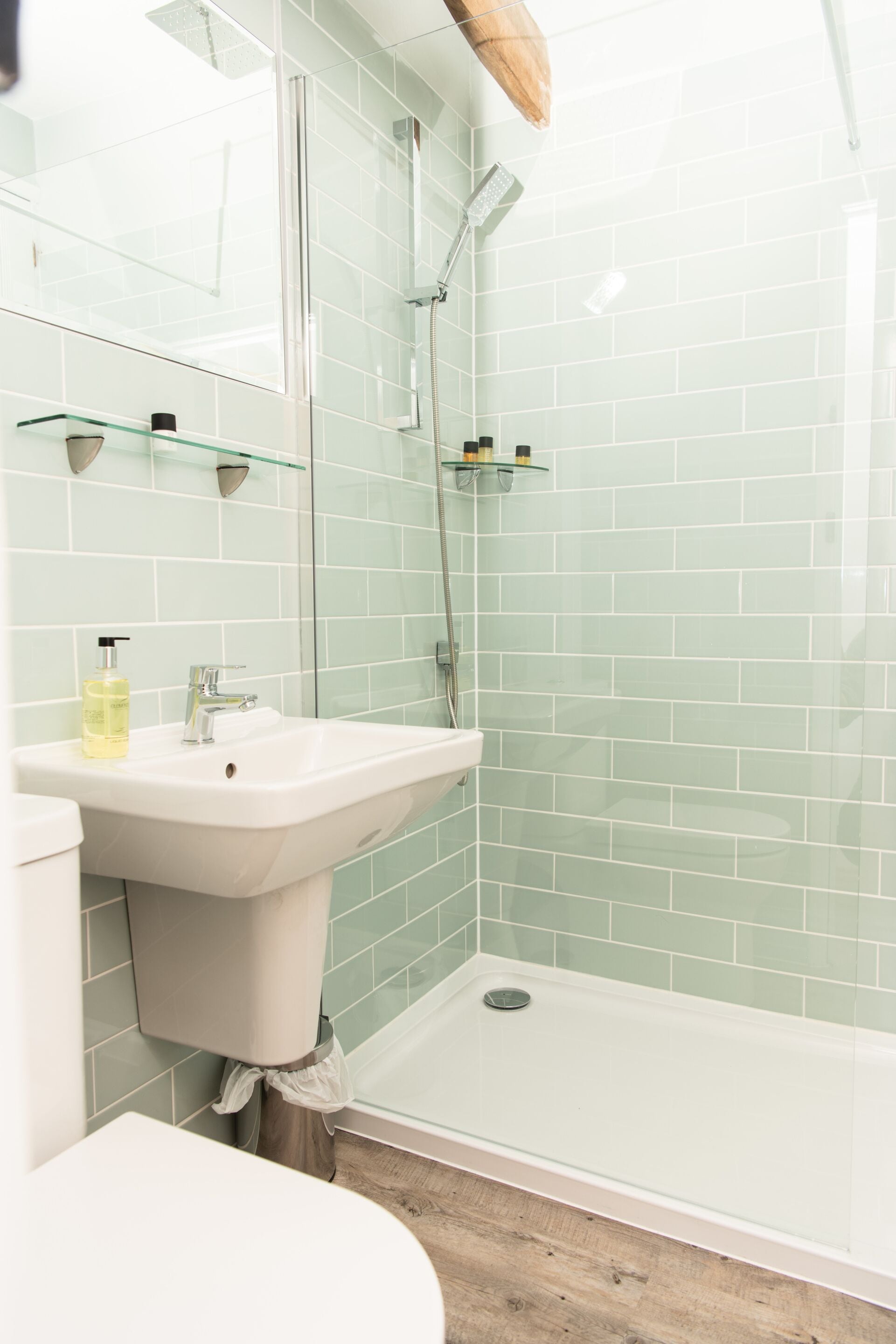 A bathroom with a glass shower enclosure, a white sink, and a toilet.