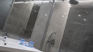 Un baño moderno con un espejo grande, un lavamanos y una ducha con cabezal de ducha manual.