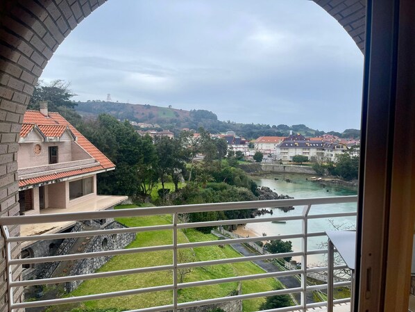 Vista desde un balcón con un muro de piedra, un río y edificios al fondo.