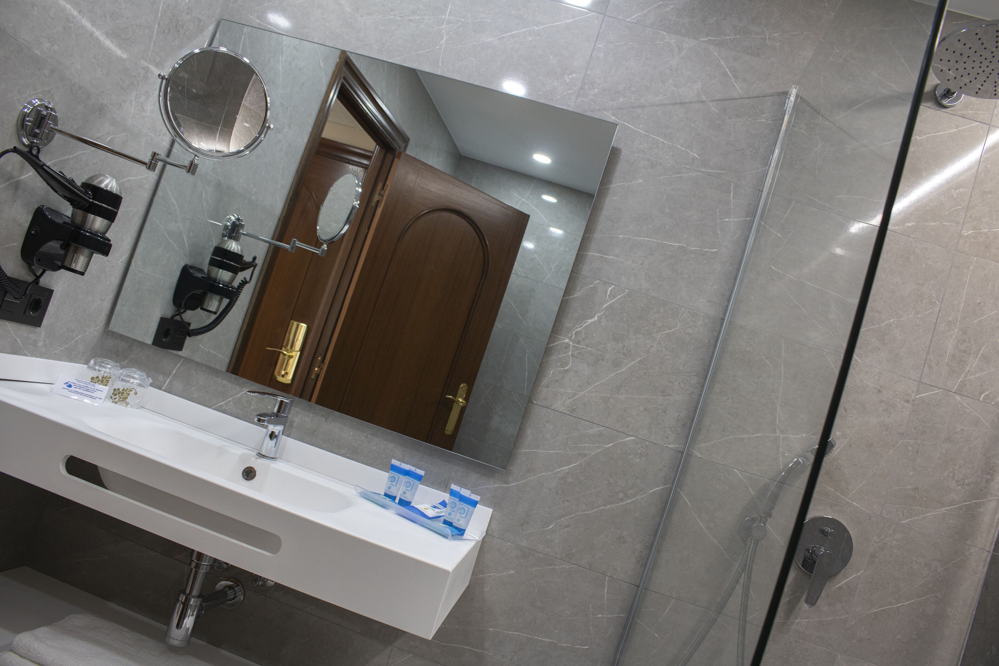 A modern bathroom with a white sink, a mirror, and a shower area.
