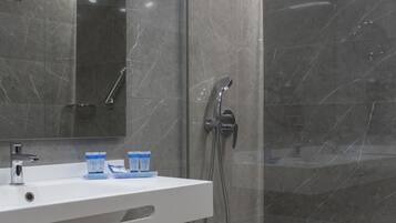 A modern bathroom with a glass-enclosed shower, a white sink, and a mirror.