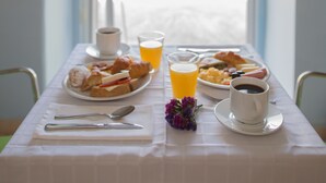 Una mesa de desayuno con platos de comida, una taza de café y un vaso de jugo de naranja.
