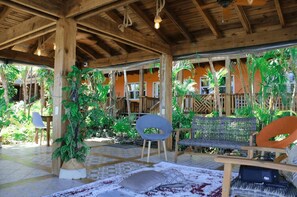 Un espacio al aire libre techado con vigas de madera, asientos y plantas en macetas.