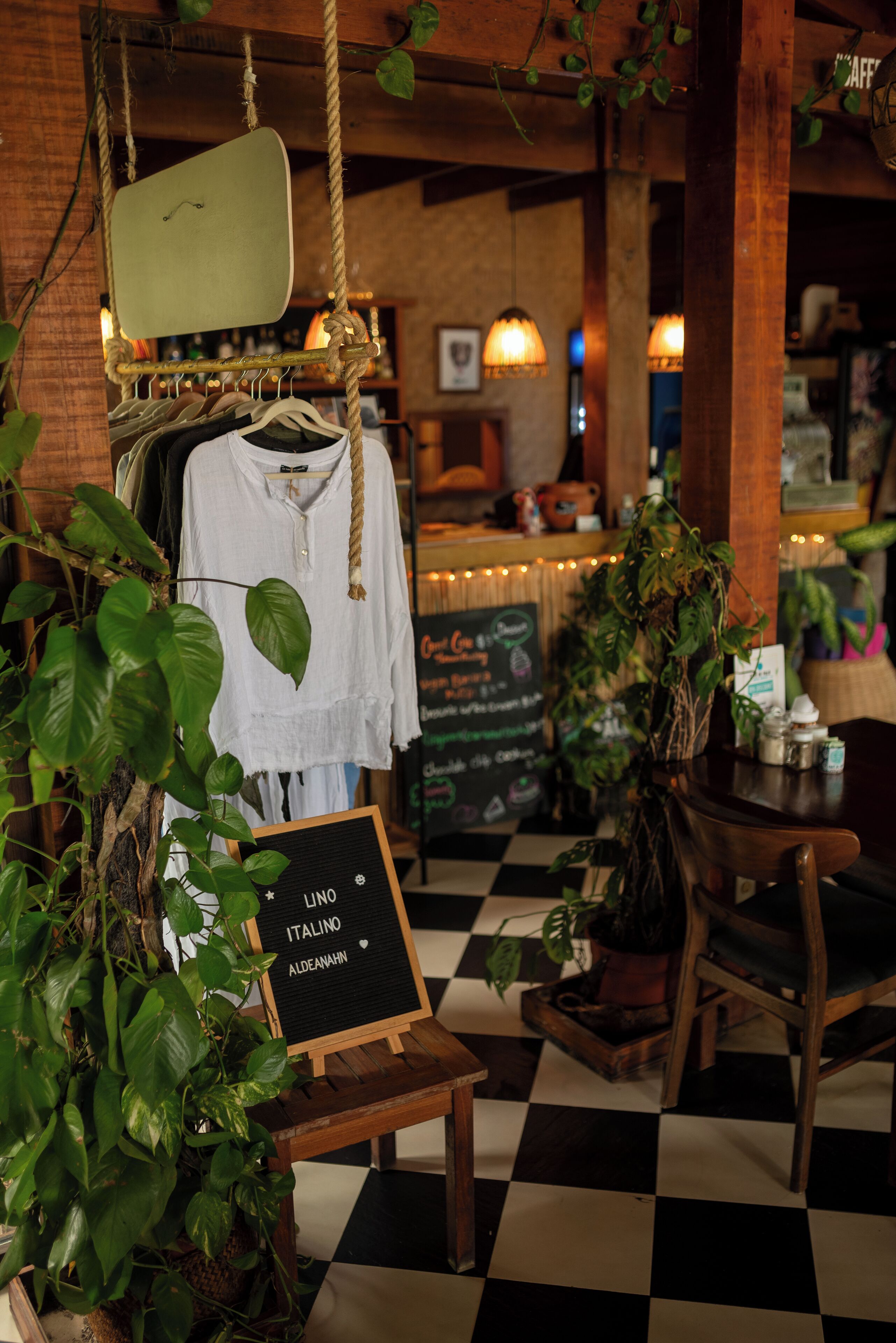 Un café acogedor con suelo a cuadros, plantas colgantes y una decoración de madera rústica.