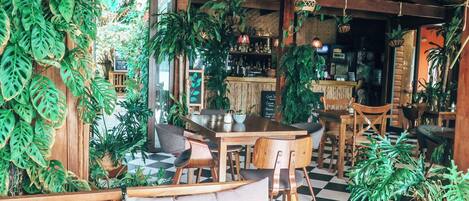 Un interior acogedor y rústico con muebles de madera, piso de cuadros y abundante vegetación.