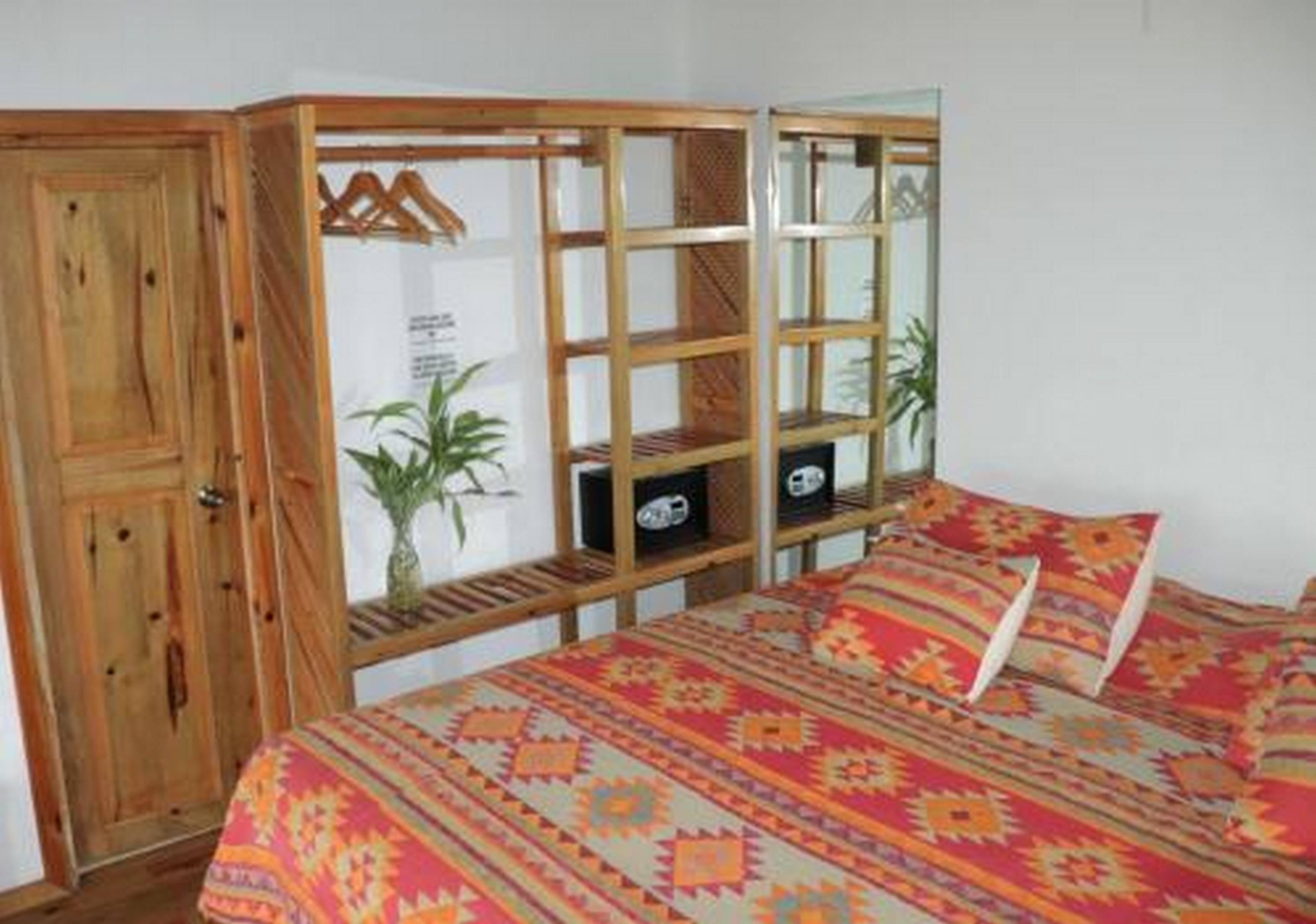 Een slaapkamer met een houten garderobe, een bed met behang en een klein wandrek met decoratieve spullen.