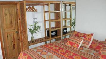 Een slaapkamer met een houten garderobe, een bed met behang en een klein wandrek met decoratieve spullen.