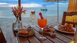 A beachside table with drinks, snacks, and a view of the ocean.