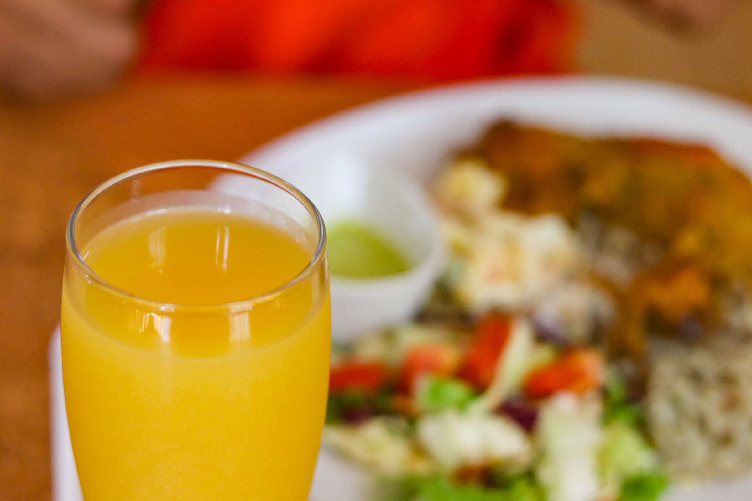 Un verre de jus d’orange et une assiette de nourriture, comprenant une salade et un plat principal.