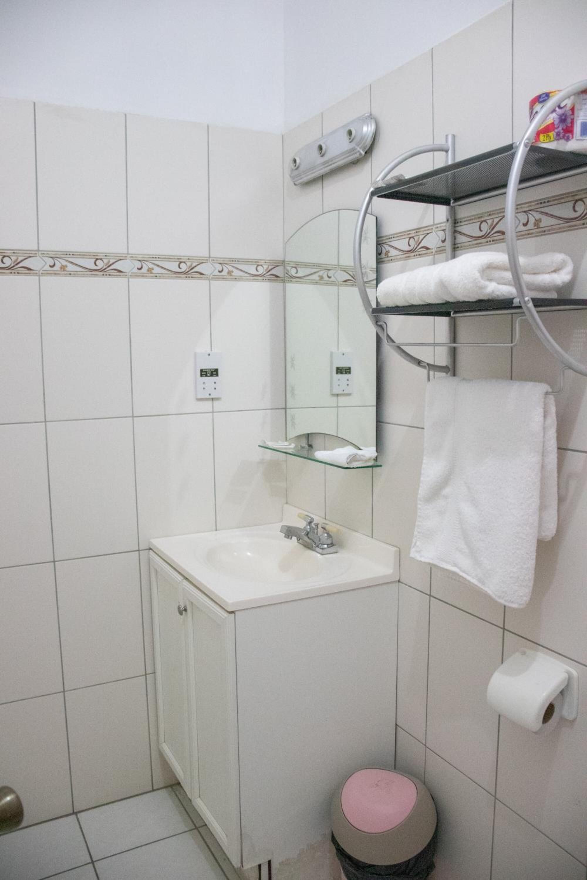 Een badkamer met een wastafel, spiegel, handdoekhouder en toilet.