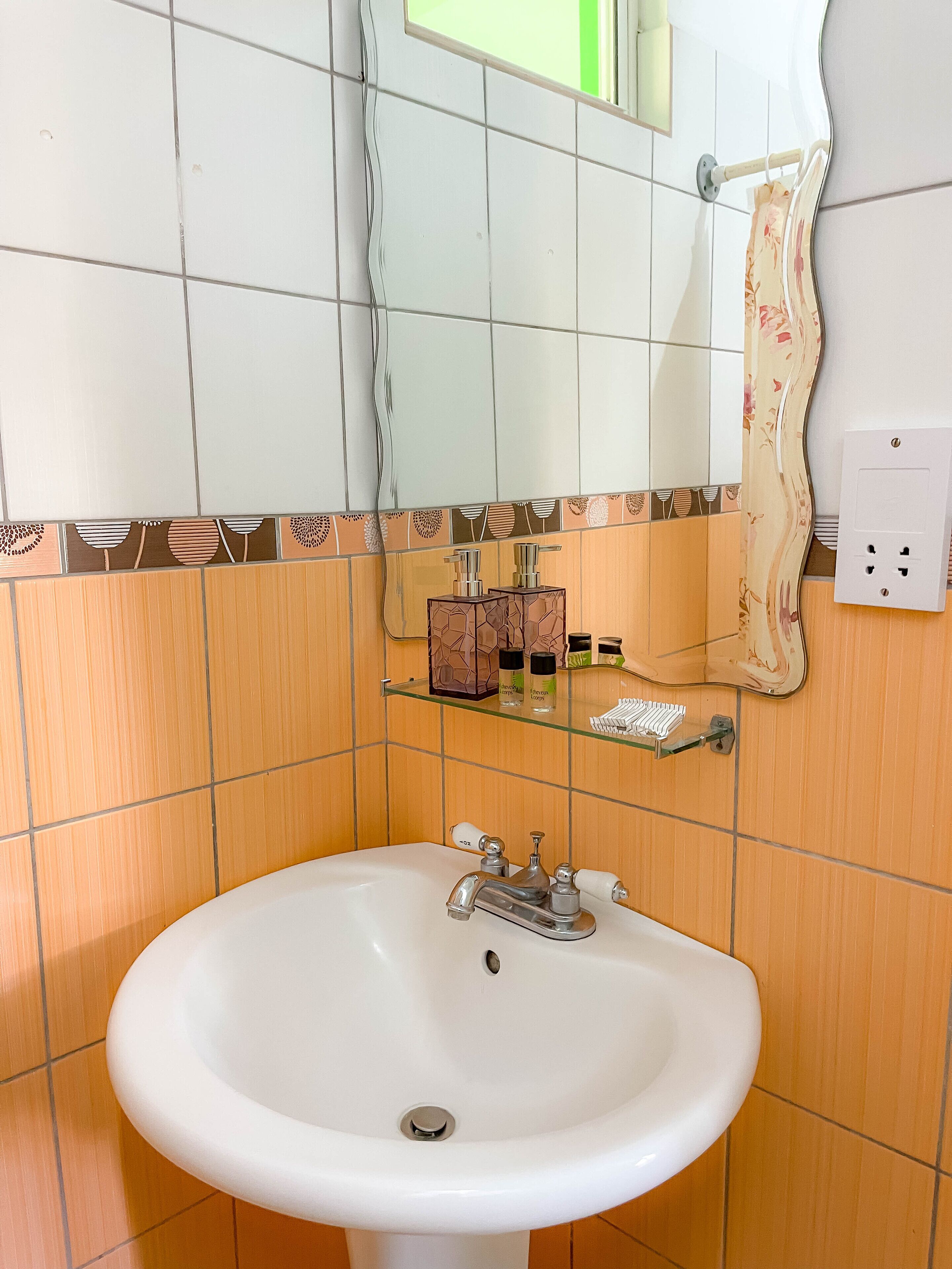 A bathroom with a white sink, a mirror, and a shelf with toiletries.