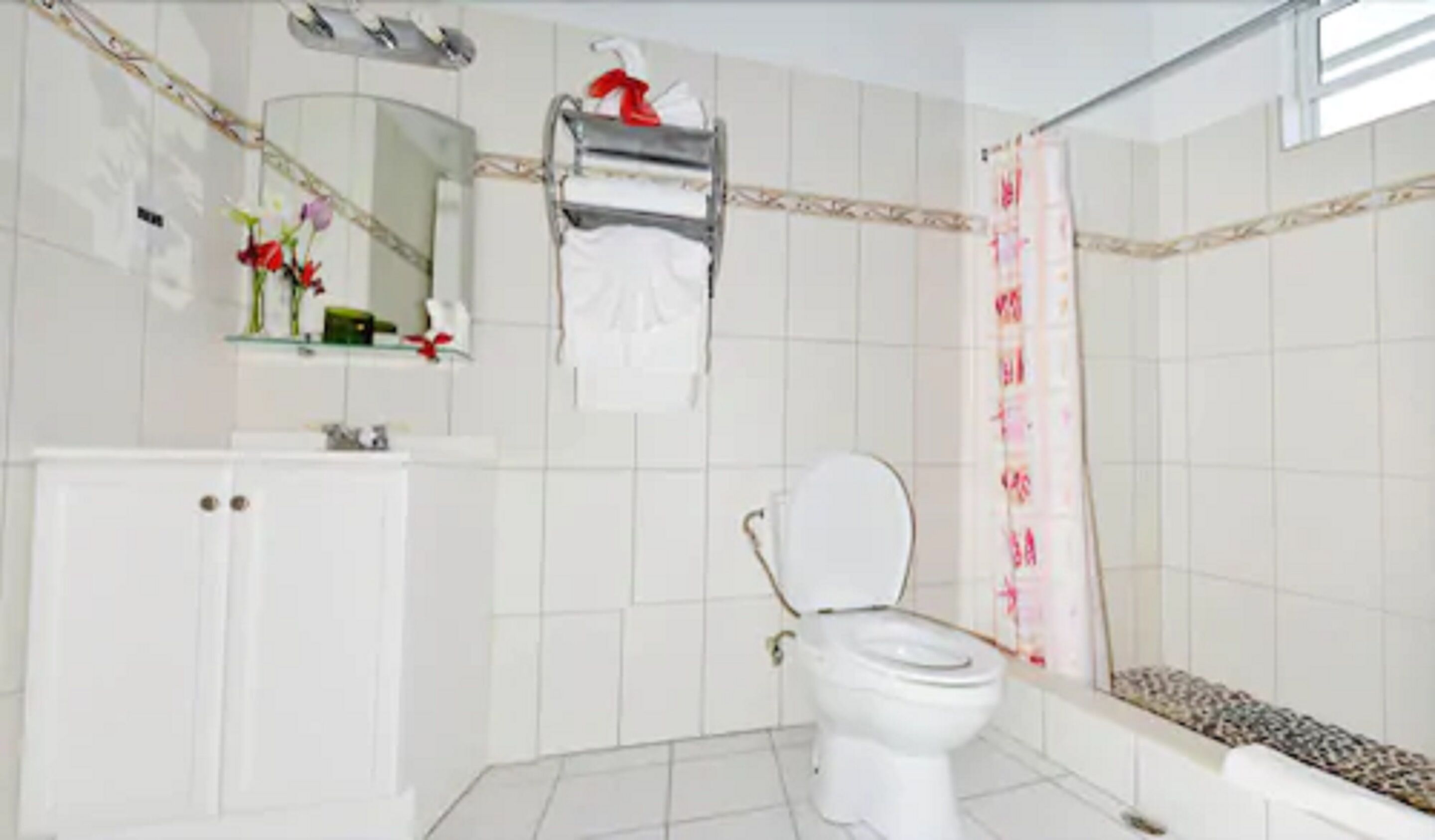 Un baño con inodoro, lavamanos, espejo y cortina de ducha.