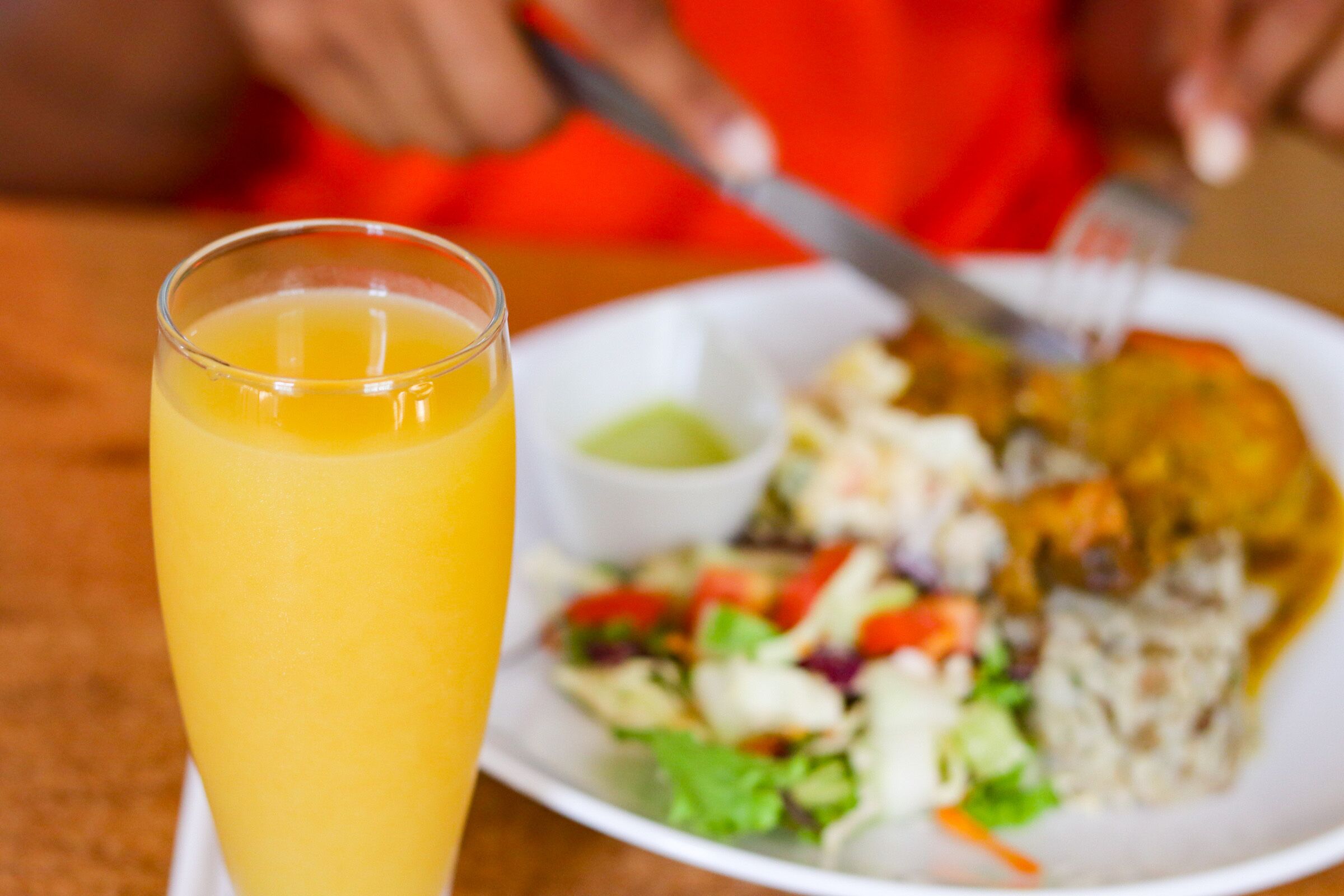 A plate of food with a side of salad and a glass of orange juice.