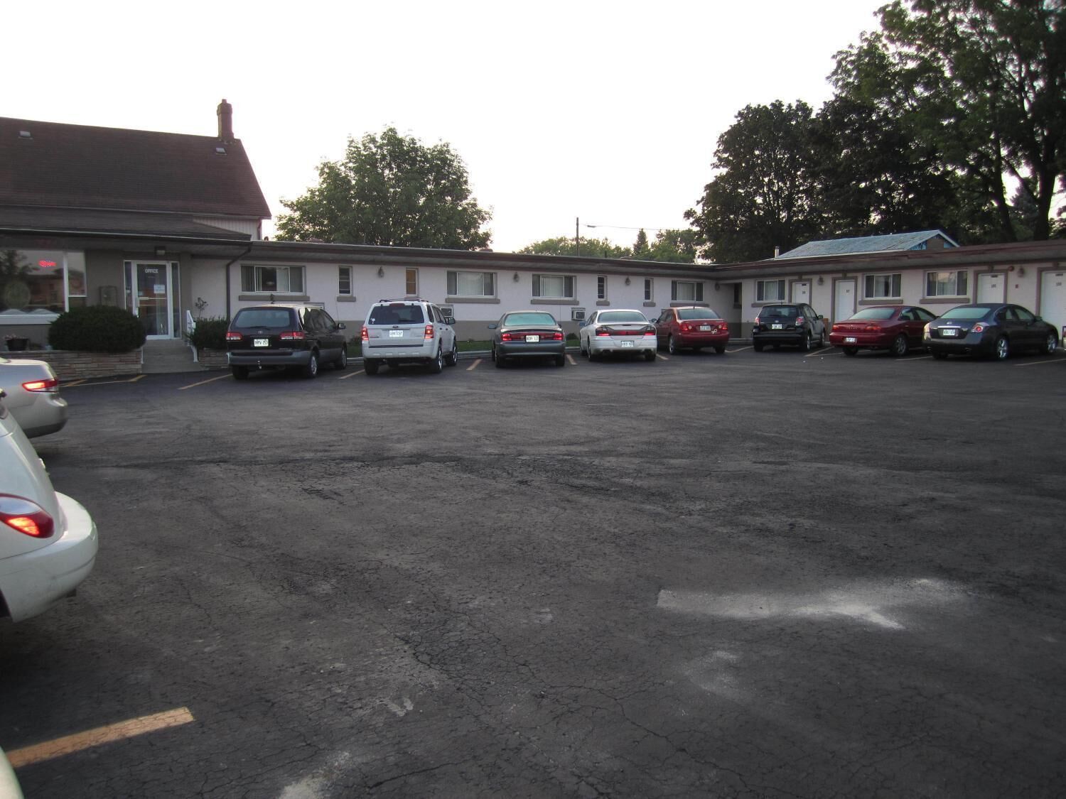 A parking lot with several cars parked in front of a building with multiple windows and a flat roof.