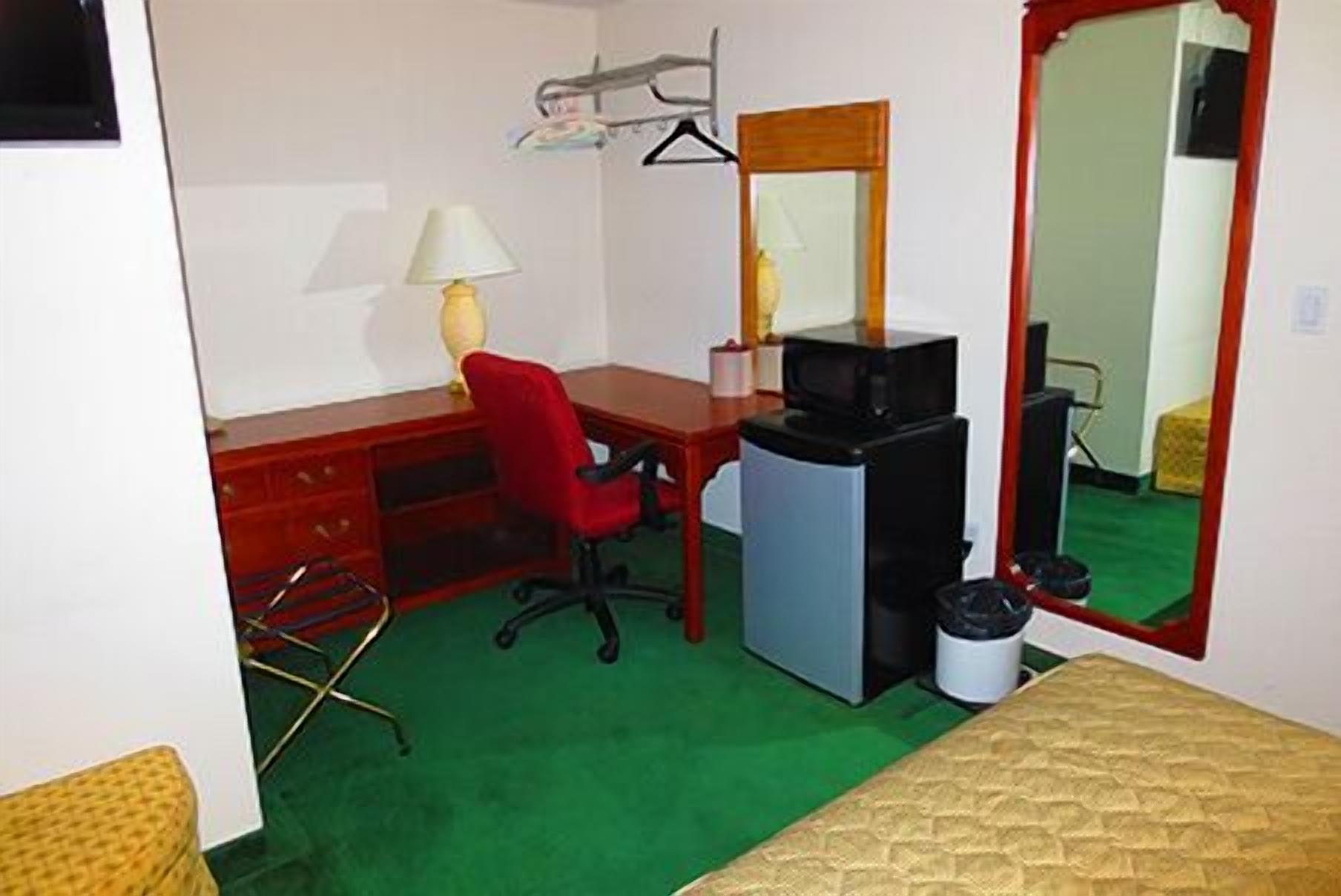 A small, compact room with a desk, chair, and a bed.