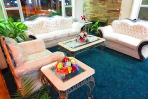 Una habitación con un sofá, una mesa de centro y una mesita con flores.