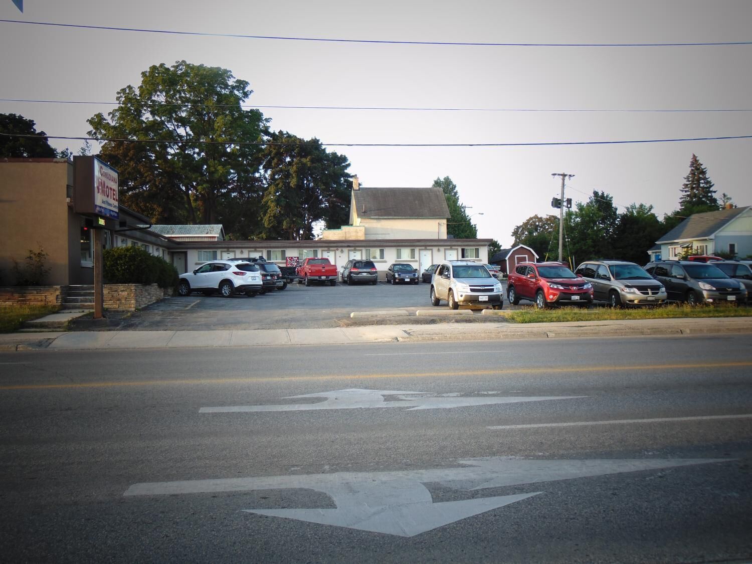 A motel with a parking lot and a building with a sloped roof.