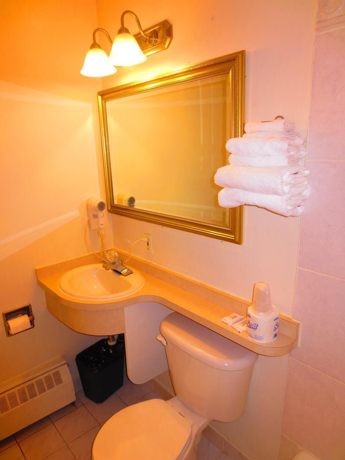 Un baño con lavamanos, inodoro y toallero.