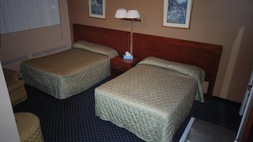 A hotel room with two beds, a nightstand, a lamp, and two framed pictures on the wall.