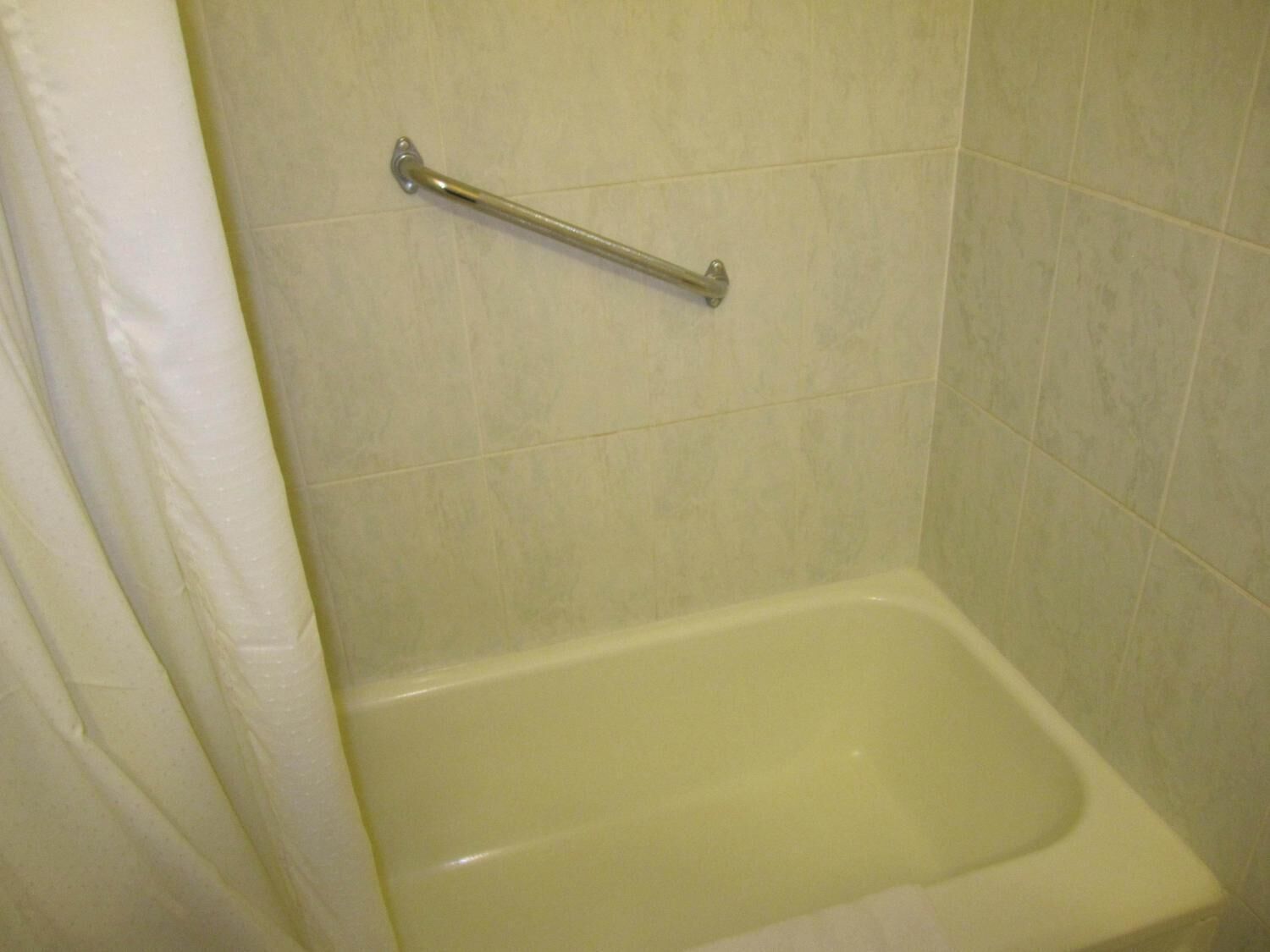 Une salle de bain équipée d’une baignoire, d’un rideau de douche et d’une barre d’appui.