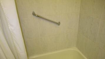 Une salle de bain équipée d’une baignoire, d’un rideau de douche et d’une barre d’appui.