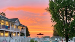 A waterfront hotel with a pool area, a covered deck, and a sunset view. - Bay Breeze Resort (Ephraim)