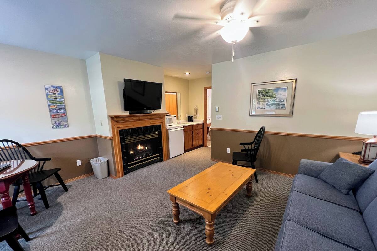 A living room with a fireplace, a television, a sofa, and a dining table.