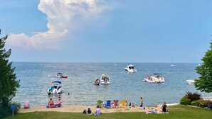 A beach with boats, chairs, and people. - Bay Breeze Resort (Ephraim)