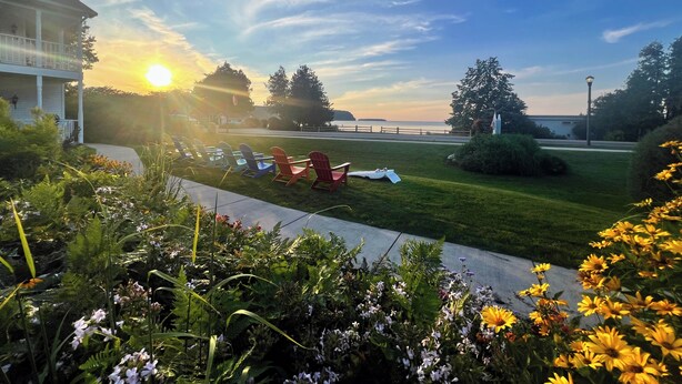 A grassy area with outdoor seating and a view of the ocean. - Bay Breeze Resort (Ephraim)