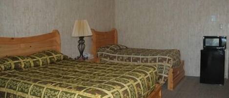A room with two beds, a small table with a lamp, and a television.