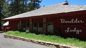 A red building labeled 'Boulder Lodge' with a stone border and green plants in front.