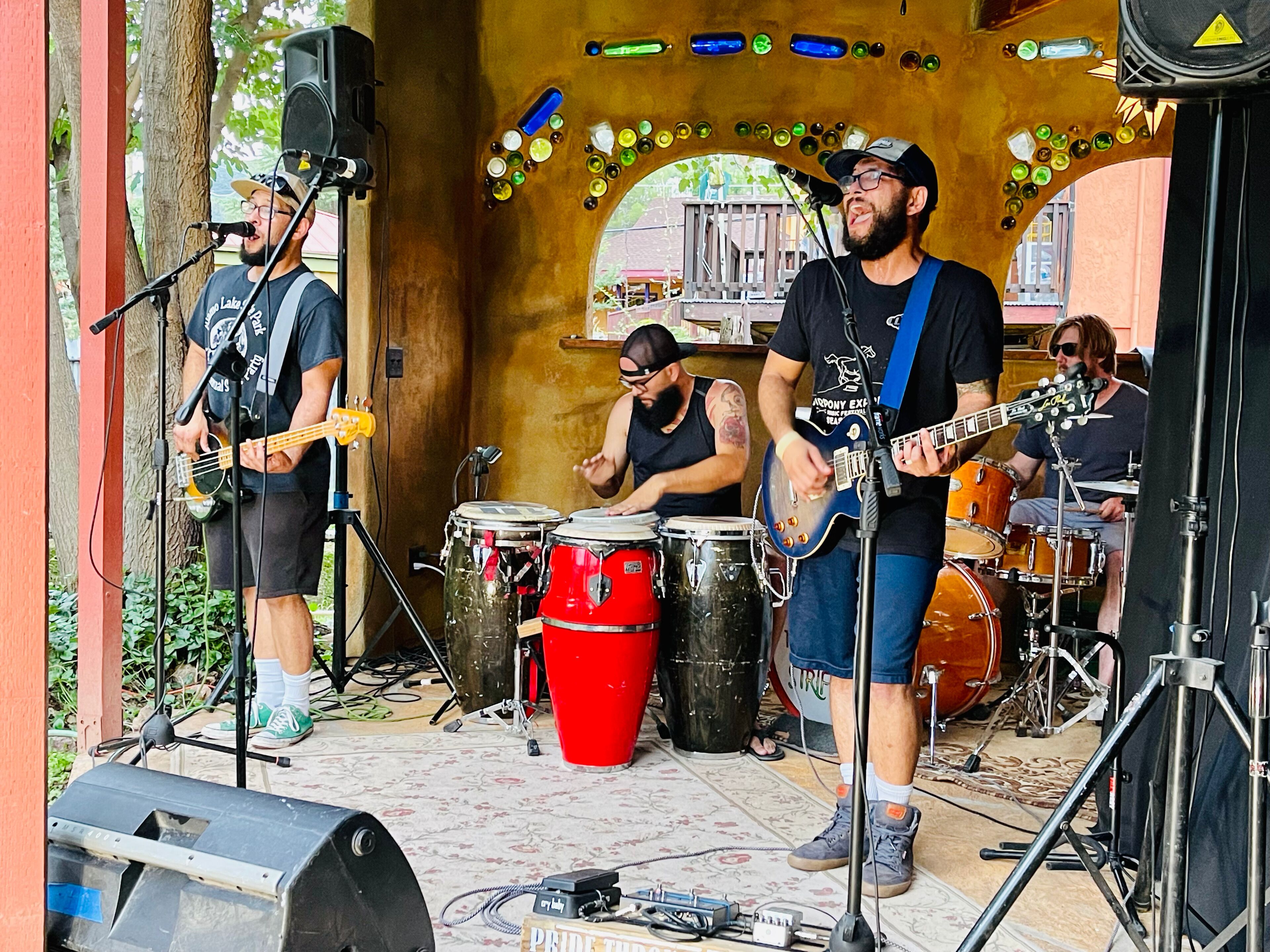 Een band treedt op op een openluchtbühne met muziekinstrumenten en apparatuur.