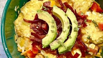 A bowl of food with avocado slices, eggs, and diced vegetables.