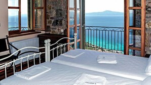 A bedroom with a bed, a window, and a view of the sea. - Diotima's Homes (Kalamata)