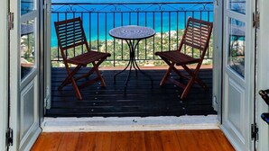 An open balcony with two wooden chairs and a small table, overlooking a coastal view with a clear sky. - Diotima's Homes (Kalamata)