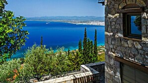 A stone building with a balcony overlooking a coastal view. - Diotima's Homes (Kalamata)