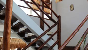 A wooden staircase with white railings and a thatched roof in the background.