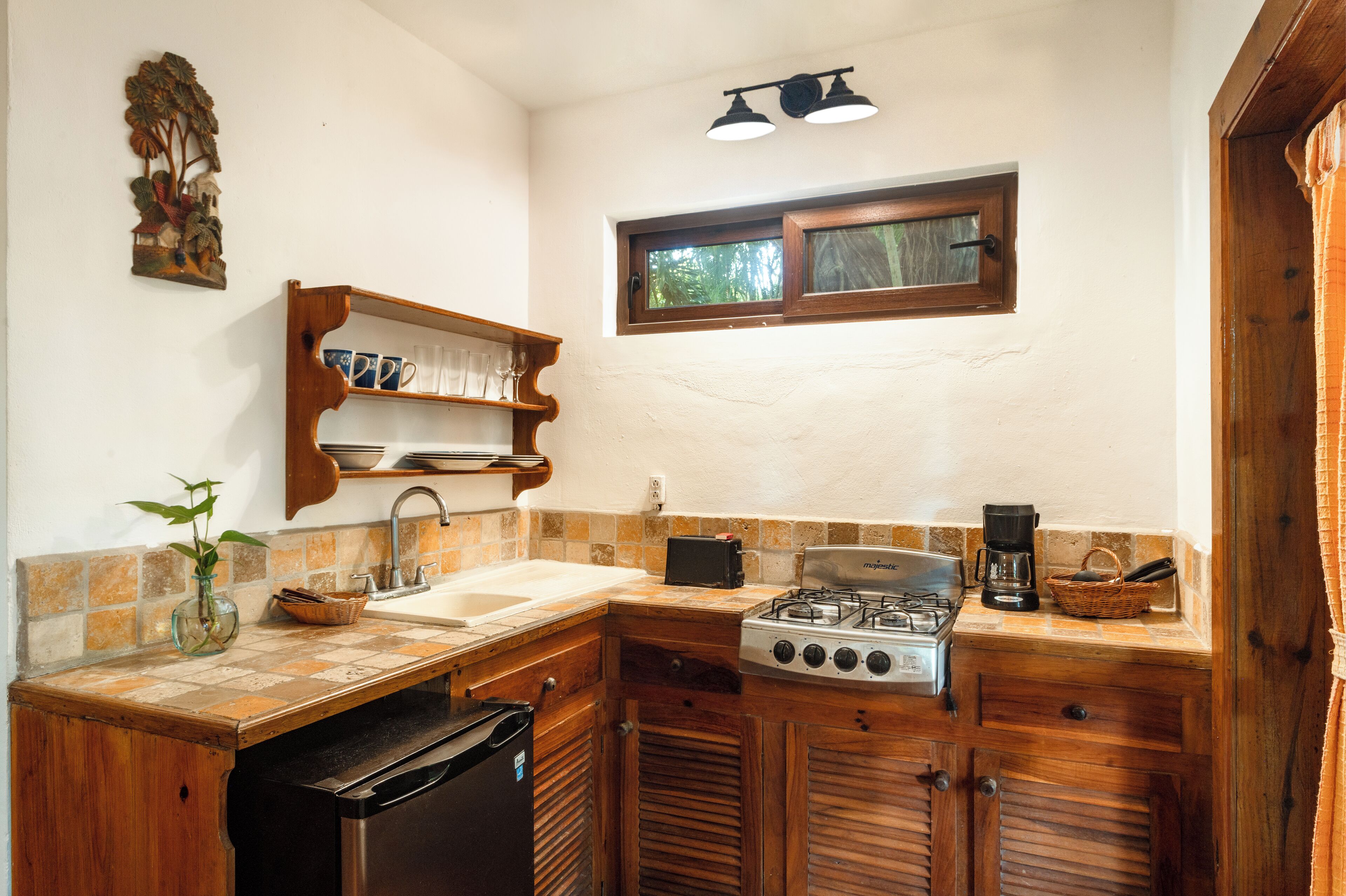 Una cocina pequeña con estufa a gas, pileta y alacenas de madera.