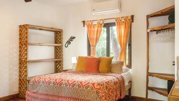 A bedroom with a bed, a wooden wardrobe, a window with curtains, and a ceiling fan.