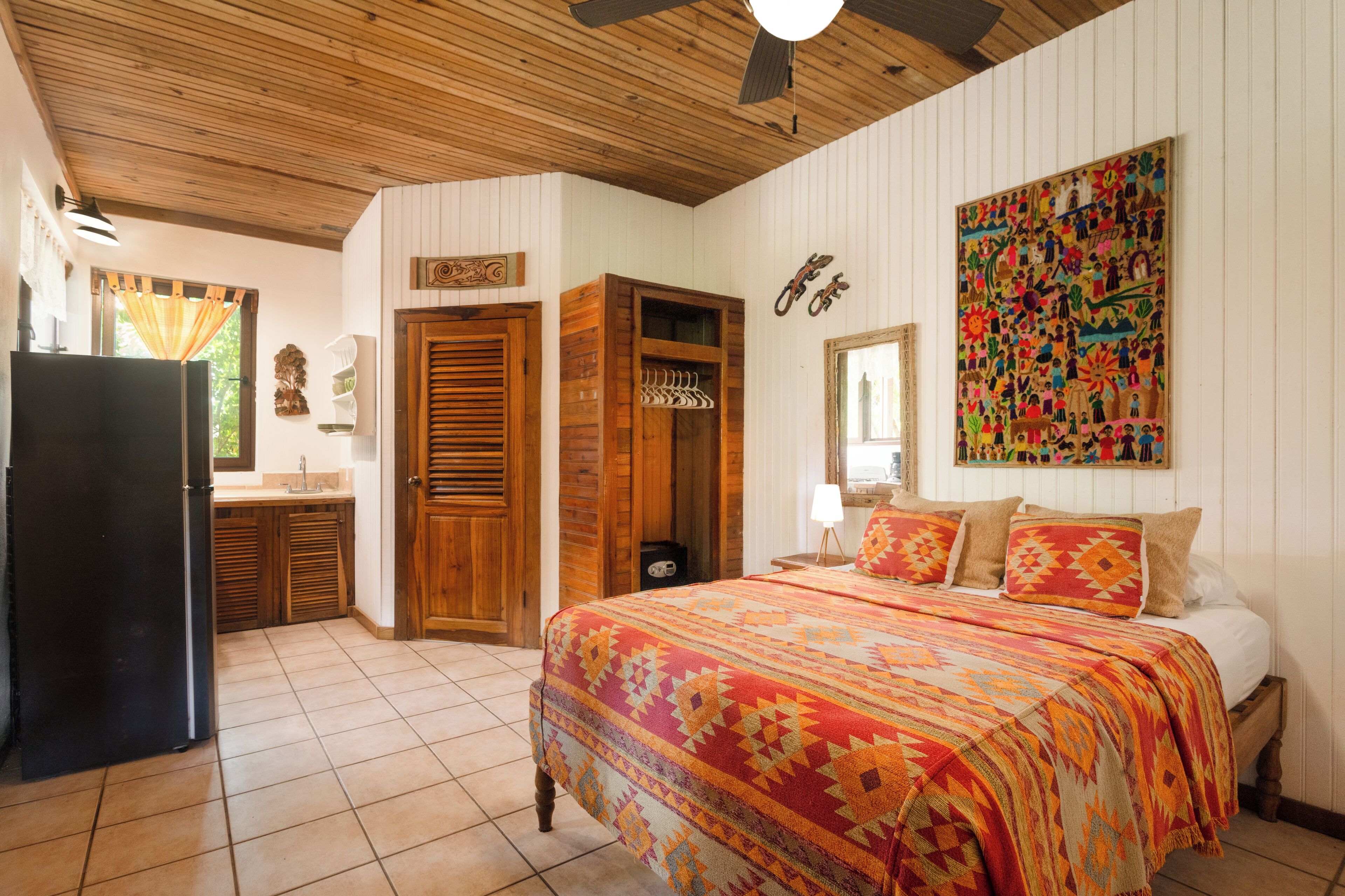 A bedroom with a bed, wooden wardrobe, and a colorful wall mural.