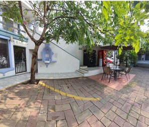 A courtyard with a tree, a reception desk, a Coca-Cola vending machine, and a glass table with chairs. - Hotel Posada Santa Fe (Zapopan)