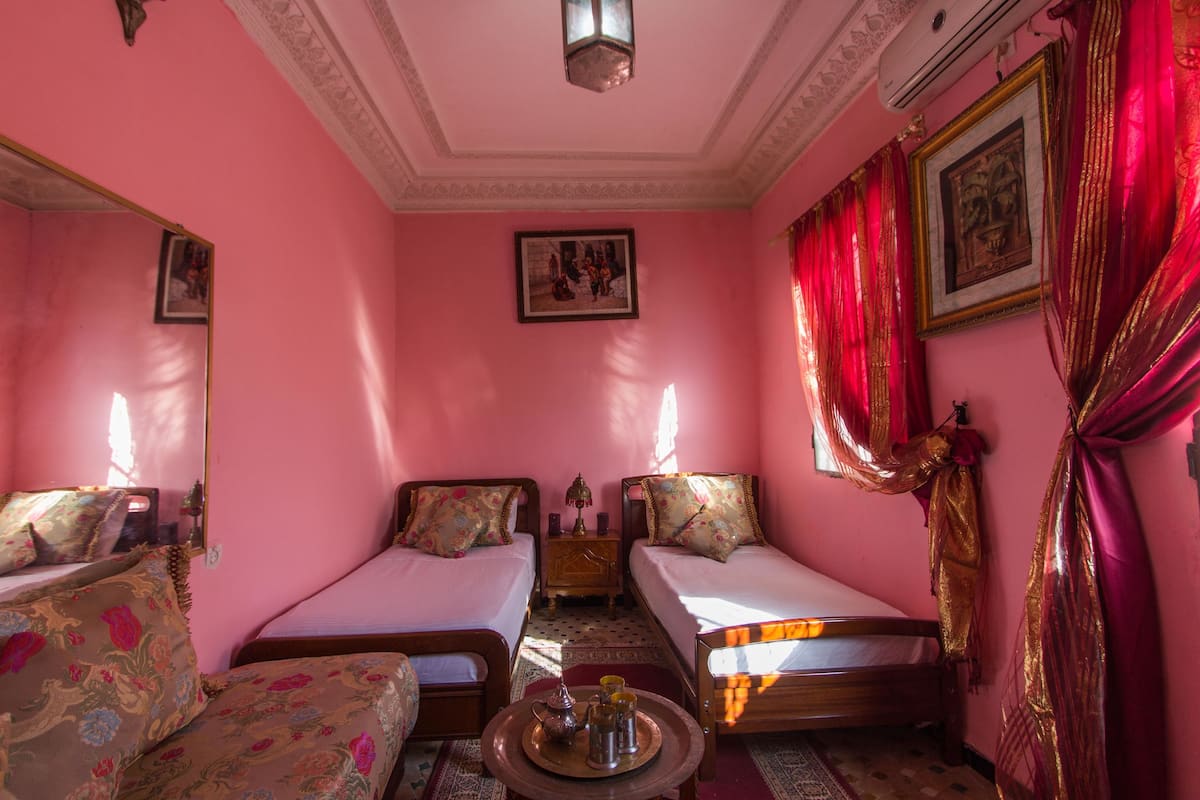 A room with two beds, a small table with a tray, and a mirror.
