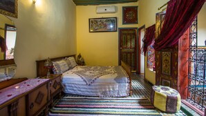 Un dormitorio con cama, cómoda, espejo y ventana con cortinas.