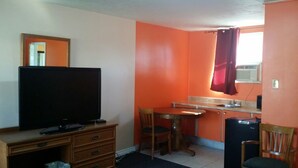 A compact room with a kitchenette, a dining table, a TV, and a refrigerator. - Lakeridge Motel (Whitby)