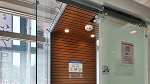 A modern office space with a glass partition, a wooden panel wall, a fire extinguisher, and a sign indicating a smoking area. - Richmond Hotel Hakataekimae (Fukuoka)