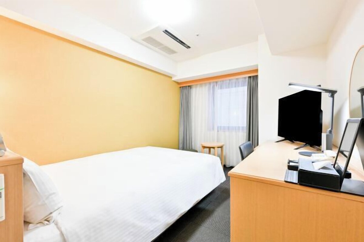 Une chambre d’hôtel équipée d’un lit, d’un bureau, d’une chaise et d’un téléviseur.