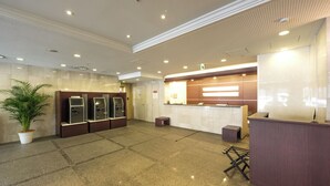 A hotel lobby with a reception desk, a large potted plant, and a seating area. - Richmond Hotel Hakataekimae (Fukuoka)