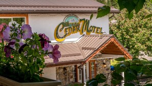 A building with a Cedar Motel sign, stone facade, and a wooden roof. - Cedar Motel (Radium Hot Springs)