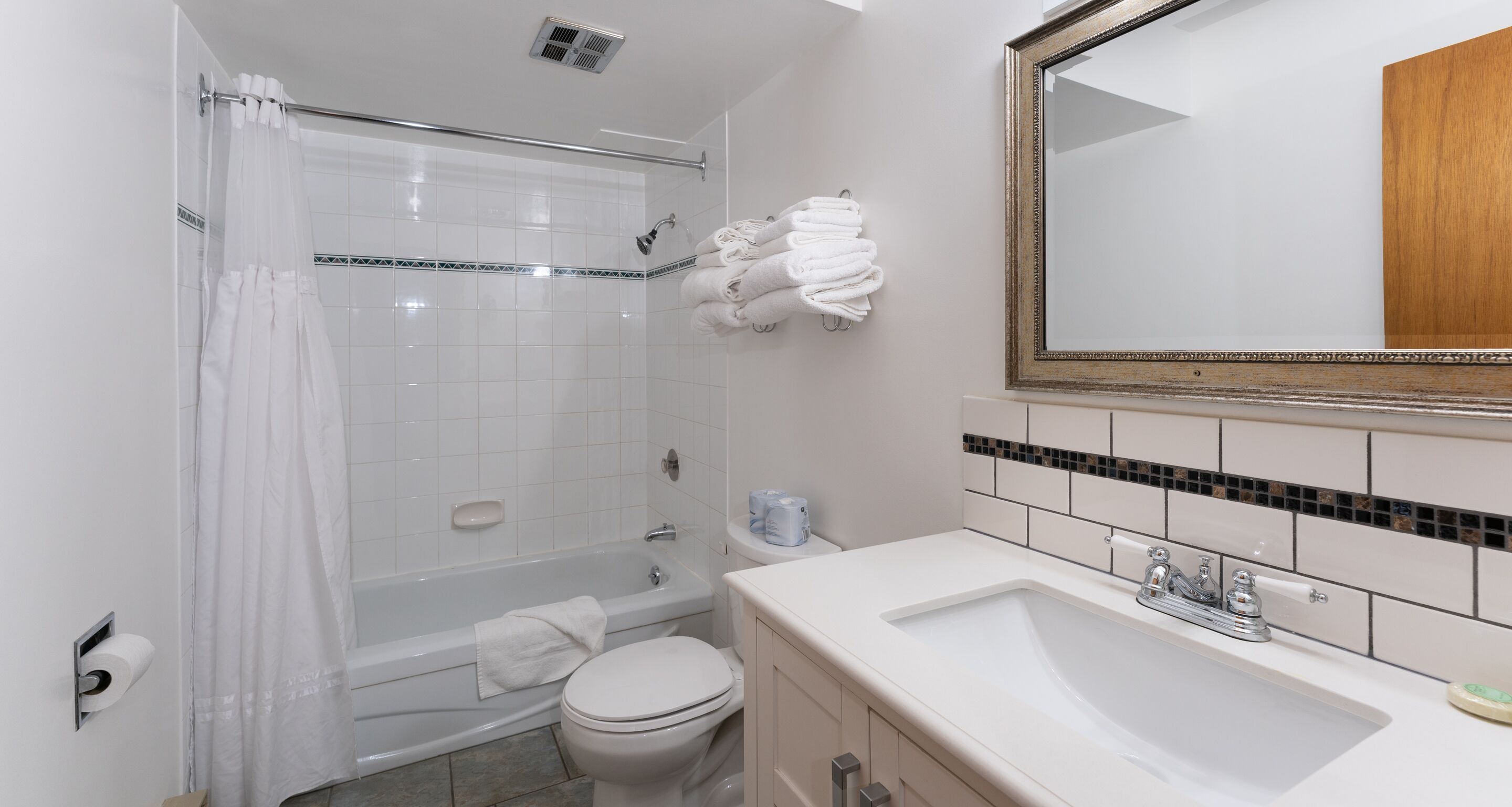 Un bagno con vasca, water, lavabo e specchio.